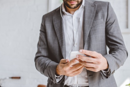 cropped image of businessman listening music with smartphone in officeの写真素材
