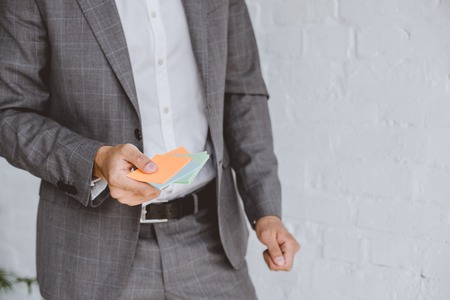 cropped image of businessman holding paper stickers in officeの写真素材