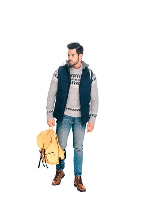 full length view of handsome young traveler holding backpack and looking away isolated on whiteの写真素材