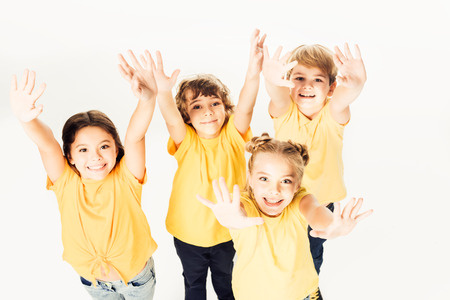 high angle view of group of happy children showing hands and smiling at camera isolated on whiteの写真素材