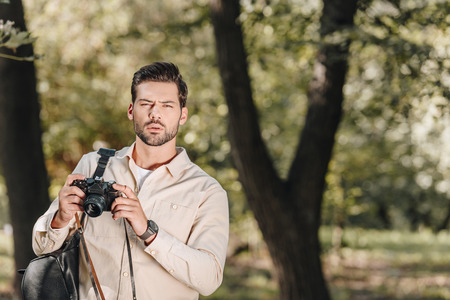 portrait of tourist with photo camera in hands in park
