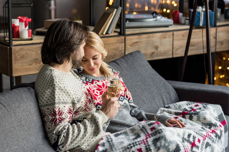 happy young couple sitting together and drinking champagne at christmas timeの写真素材