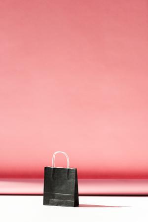 one black shopping bag on pink with copy spaceの写真素材