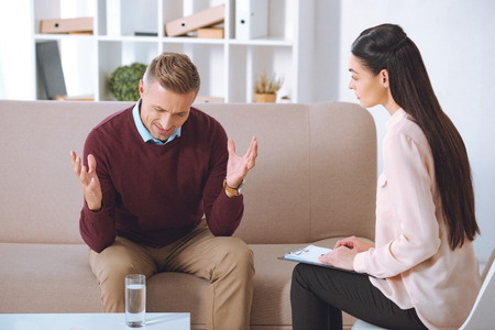 male patient having therapy appointment at psychologist officeの写真素材