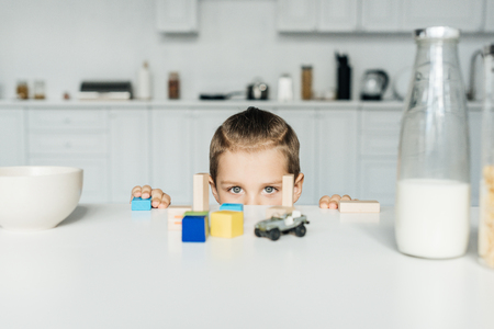 partial view of little boy playing with toys in kitchen at homeの写真素材