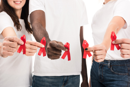 cropped shot of group of people in blank white t-shirts holding aids awareness red ribbons isolated on whiteの写真素材