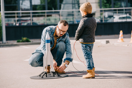 father and little son launching model rocket together outdoorの写真素材