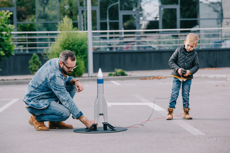 father and little son playing with model rocket outdoorの写真素材