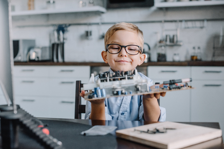 adorable boy holding motherboard at table at home