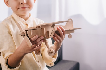 cropped shot of little boy holding wooden toy plane at homeの写真素材