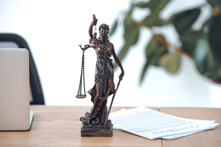 close-up view of lady justice statue, contract and laptop on tableの写真素材
