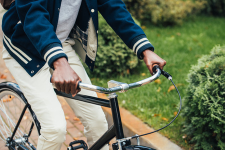 cropped view of african american man riding bicycle in parkの写真素材