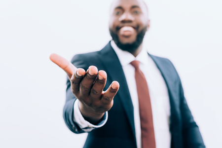 selective focus of smiling african american businessman gesturing isolated on whiteの写真素材