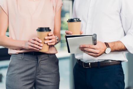 cropped shot of business colleagues with coffee to go in conference hall