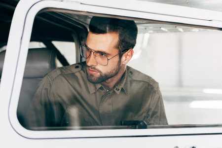stylish man in green jacket and eyeglasses boarding in airplaneの写真素材