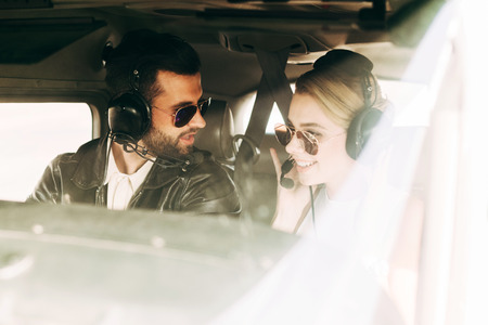 male pilot in headset and sunglasses talking to girlfriend in cabin of airplaneの写真素材
