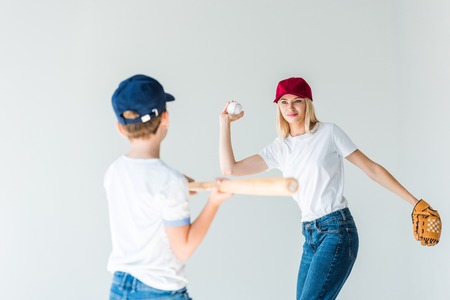 attractive mother pitching baseball ball to son with baseball bat isolated on whiteの写真素材