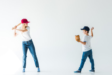side view of son pitching baseball ball to mother with baseball bat isolated on whiteの写真素材
