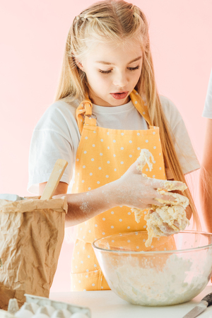 adorable teen child kneading dough isolated on pinkの写真素材