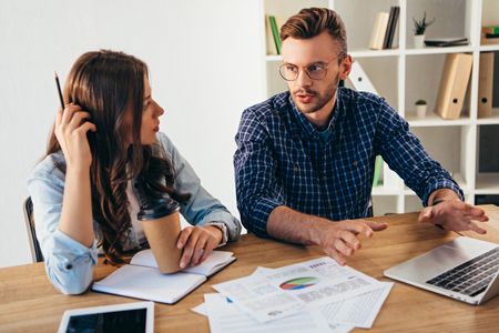 Business colleagues taking part in webinar together at workplace with papers and notebook in officeの写真素材