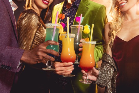 Cropped view of friends holding alcohol cocktails on partyの写真素材
