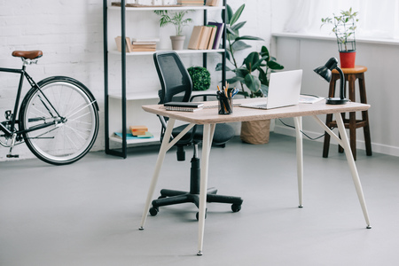 Interior of modern business office with table, laptop and bikeの写真素材