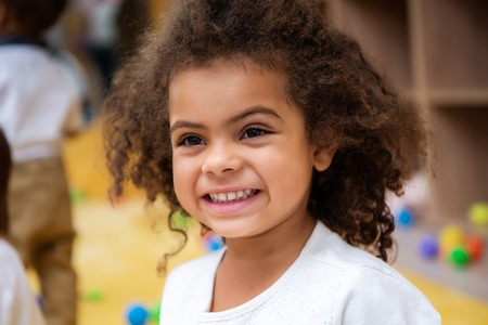 Portrait of adorable smiling African American kid looking away in kindergartenの写真素材