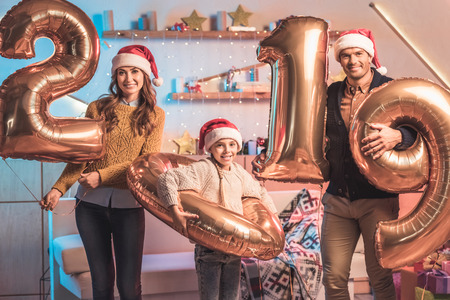 Happy parents with daughter in Santa hats holding 2019 new year golden balloonsの写真素材