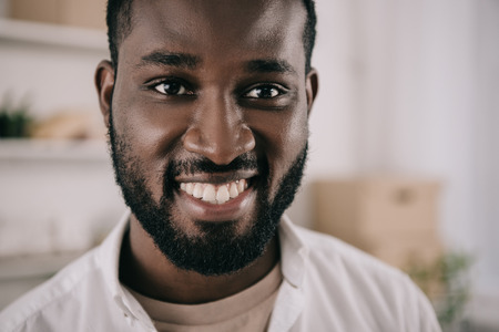 Portrait of smiling bearded handsome African American businessman looking at camera in officeの写真素材