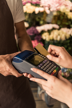 Cropped image of customer paying for flowers with credit card at storeの写真素材