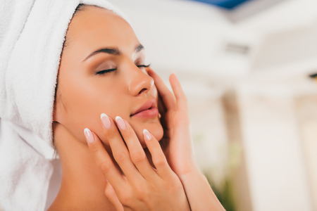 Attractive woman in towel on head touching perfect clean faceの写真素材