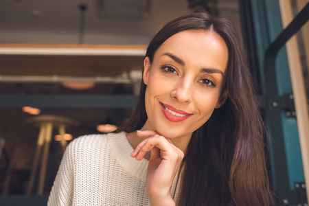 Close up portrait of pretty young woman looking at camera in cafeの写真素材