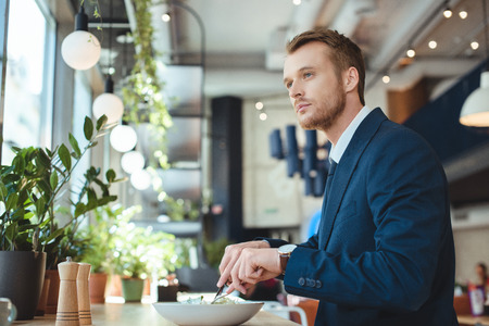 Side view of thoughtful businessman looking away while having lunch in cafeの写真素材