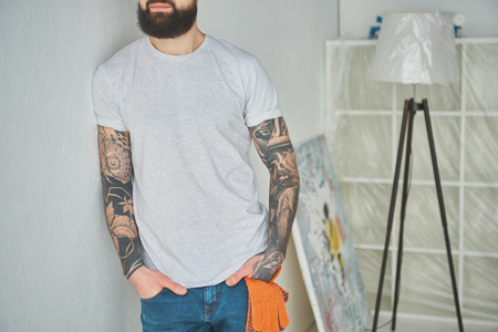Cropped shot of bearded tattooed man leaning at wall in new houseの写真素材