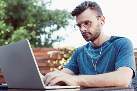 Handsome man taking part in webinar at table in parkの写真素材