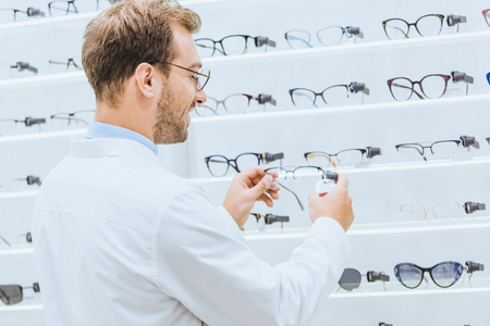 Oculist taking eyeglasses from shelves in ophthalmic shopの写真素材