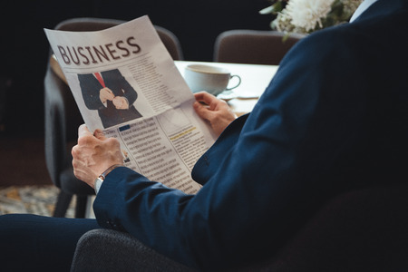 Partial view of businessman with newspaper during coffee break in cafeの写真素材