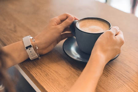 Cropped image of woman sitting with coffee cup at table in cafeの写真素材