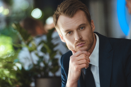 Portrait of pensive businessman looking at camera in cafeの写真素材