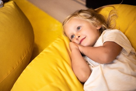 Adorable kid lying on bean bag chair in kindergartenの写真素材