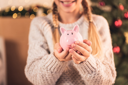 Cropped view of female youngster holding pink piggy bankの写真素材