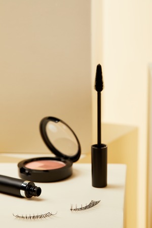 close-up shot of mascara with false eyelashes and shimmer on beige
