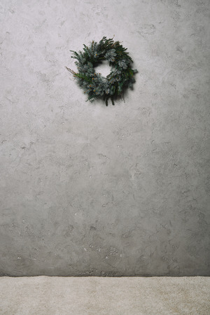 green fir wreath for Christmas decoration hanging on grey wall in roomの写真素材