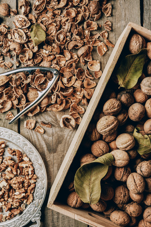top view of walnuts in box, nutcracker and nutshells on wooden tableの写真素材