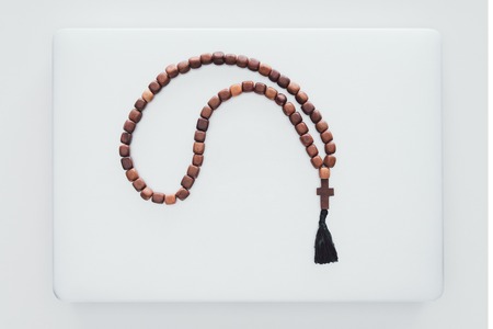 top view of beads lying on closed laptop on white surface