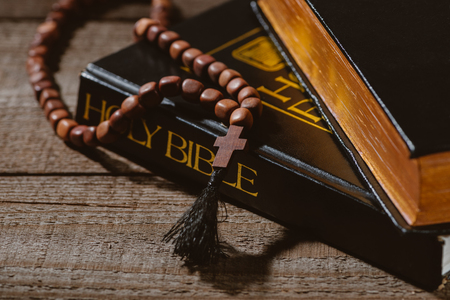 close-up shot of holy bibles with beads on wooden tableの写真素材
