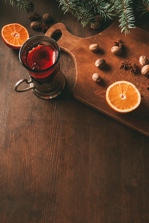 hot mulled wine with spices and orange in glass cup on wooden cutting boardの写真素材