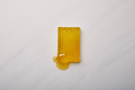 top view of handmade soap in shape of honeycomb on white marble surfaceの写真素材