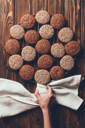 cropped image of woman putting sweet baked cookies on wooden table in bakeryの写真素材
