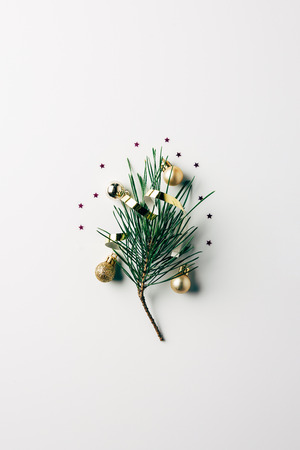 top view of little pine tree branch with ribbon and christmas toys on white surfaceの写真素材